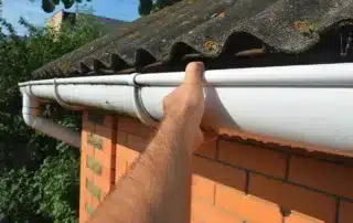 Conifer Gutter Services: Hand checking roof gutter condition outdoors to ensure proper maintenance and prevent potential water damage to your home.