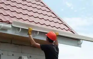 Conifer Gutter Services: Worker installing a rain gutter on a tiled roof to ensure effective water drainage and protect your home from damage.