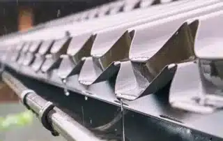 Rainwater flowing from a metal roof gutter system, effectively channeling water. Conifer Gutter Services ensures reliable installation and maintenance