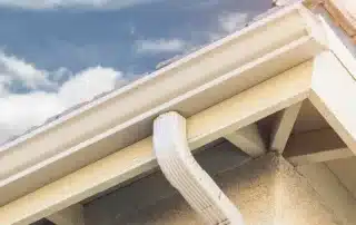 Conifer Gutter Services: House roof with guttering against a clear blue sky, ensuring proper drainage and protecting your home from water damage.
