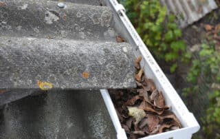 Clogged roof gutter filled with dry leaves