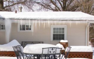 Snow-covered house with icicles and patio furniture. Patio Icicles Hazard? Heated Outlet + Diverter to Safe Zone