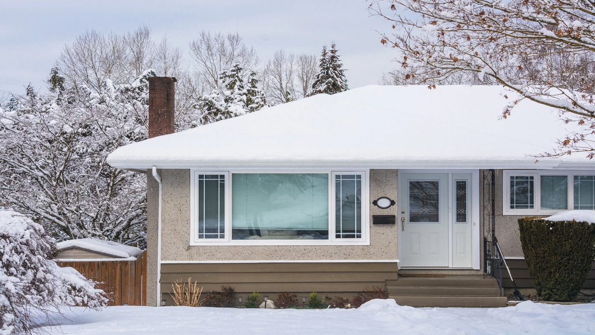 Securing Your Home Against Winter Leaks Entrance of family house with front yard in snow. Residential house on winter cloudy day