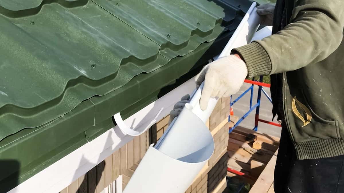 The Right Gutter Pitch Simple Math Most Installs Get Wrong Worker installing a roof gutter system.